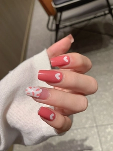 Detail of square-shaped pink heart nail wraps with glossy finish on hand model