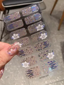Détail de stickers à ongles dégradés avec paillettes argentées et motifs de fleurs blanches
