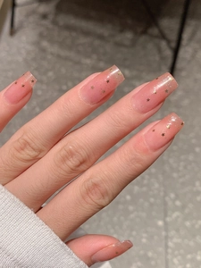 Détail de stickers à ongles dégradé rose pailleté avec étoiles dorées et pull blanc
