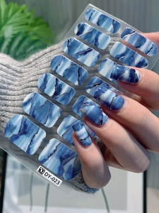 Detail of self-adhesive nail stickers with blue marble texture and gold glitter accents