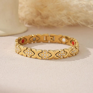 Détail macro du bracelet trèfle doré avec incrustations de cristaux et aimants de santé