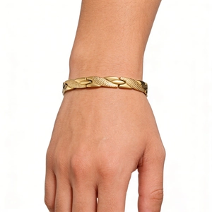 Close-up of golden dragon scale pattern link bracelet on wrist with polished metal finish