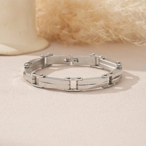 Détail d'un bracelet industriel en métal argenté avec maillons sur une surface sablonneuse