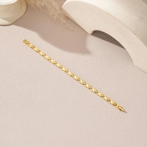 Elegante goudkleurige roestvrijstalen armband met gedraaide schakels op een basisachtergrond