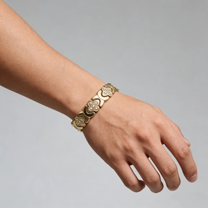 Gros plan d'un bracelet trèfle doré avec micro-pavé de cristaux sur le poignet
