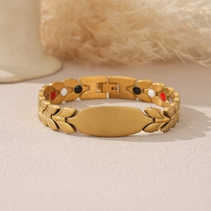 Macro detail of golden magnetic bracelet featuring curved nameplate and leaf-style link band