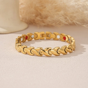 Detail of gold fishtail magnetic therapy bracelet with red and white circular inserts