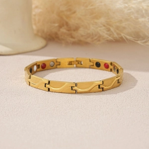 Details eines goldenen Magnettherapie-Armbands mit Wellenmustern und Energiesteinen