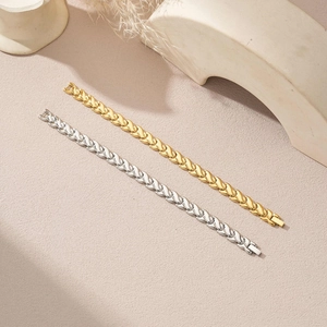 Polished fishtail link bracelets in gold and silver steel on a minimalist background