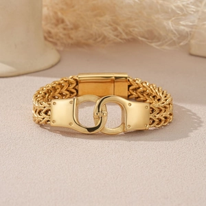 Detailed close-up of gold wheat chain bracelet with punk style handcuff clasp design