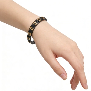 Close-up of black and gold geometric link bracelet worn on wrist for men and women