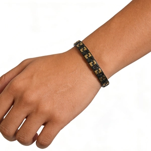 Close-up of black and gold stainless steel chain bracelet with magnetic health elements