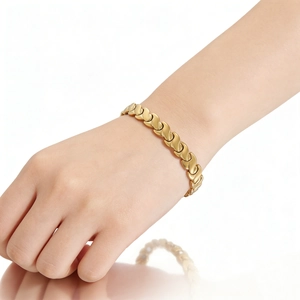 Close-up of golden fishtail magnetic bracelet with polished links on a model wrist