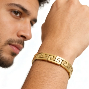 Close-up of gold stainless steel men's bracelet with Greek key cutout patterns