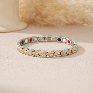 Detail view of gold-plated stainless steel magnetic therapy bracelet on a sandy surface