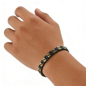 Men's matte black and gold stainless steel chain bracelet worn on a wrist