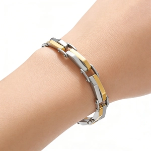 Gros plan détaillé d'un bracelet à maillons industriels bicolore argent et or texturé losange