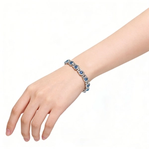 Détail d'un bracelet chaîne argenté avec zircons bleus porté sur un poignet