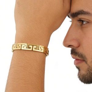 Macro detail of men's gold stainless steel bracelet featuring an elegant Greek Key pattern