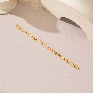 Détail du bracelet géométrique doré avec maillons en V et incrustations colorées