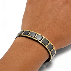 Close-up of gold and black nail-shaped magnetic bracelet on a male wrist