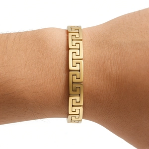 Macro shot of gold stainless steel bracelet featuring classic Greek meander pattern detail