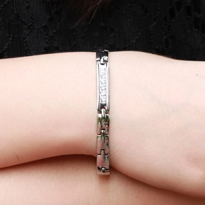 Dettaglio del bracciale magnetico in titanio argento con zirconi su pizzo nero di fondo