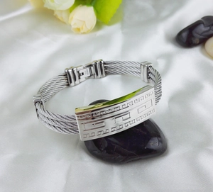 Detailed macro view of silver stainless steel cable bracelet with Greek key motif