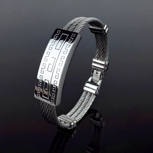 Macro detail of men's stainless steel cable bracelet with Greek key pattern engraving