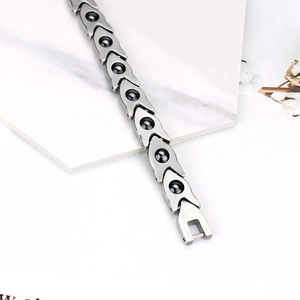 Détail macro du bracelet magnétique en acier avec pierres noires sur support marbre