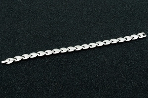 Macro detail of silver magnetic therapy steel bracelet with flame leaf link texture