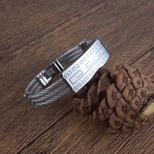 Detailed close-up of a men's stainless steel cable bracelet with Greek key pattern