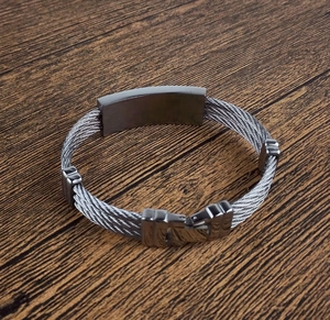 Close-up of a triple-strand woven stainless steel cable bracelet with a center metal plate