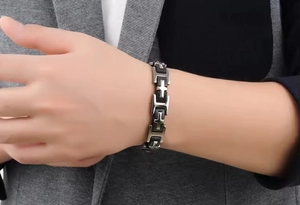 Men's titanium steel bracelet with black links and cross relief on a suit sleeve