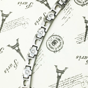 Macro detail of silver titanium steel bracelet with baby footprint charms and cubic zirconia