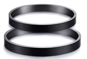 Close-up of dual matte black titanium steel bracelets with a brushed metal finish