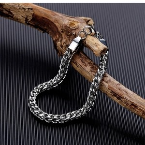 Macro shot of silver titanium steel wheat chain bracelet hanging on a wooden stand