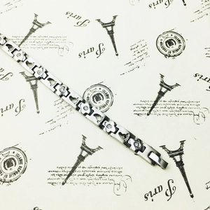 Detail of silver steel bracelet with flower and footprint links and clear crystals