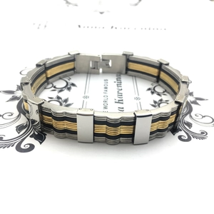 Detail of multi-tone stainless steel men's bracelet with gold accents and folding clasp