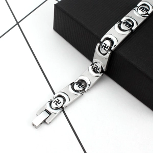 Bracelet chaîne homme en acier titane poli avec motifs noirs sur une boîte texturée