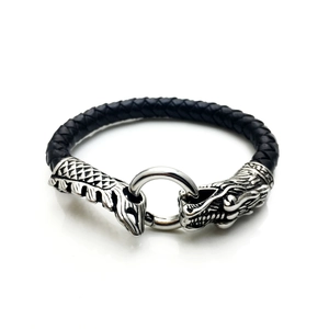 Détail de têtes de dragon en argent sur un bracelet en cuir tressé noir pour homme