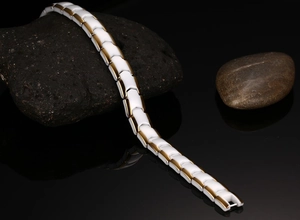 Elegant white ceramic and gold link bracelet with black stone inlay on mirror background
