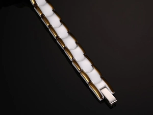 Macro shot of H-shaped white ceramic links and golden metal clasp on stylish bracelet