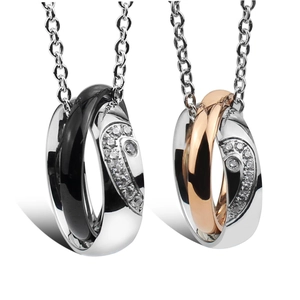 Close-up of interlocking titanium steel couple necklaces with cubic zirconia heart halves