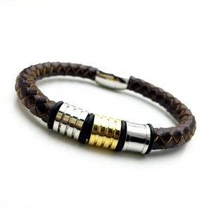 Détail macro du bracelet en cuir tressé marron avec anneaux en métal argenté et doré