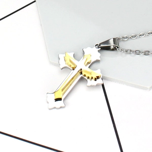 Détail macro d'une aile d'ange dorée sur pendentif croix argenté avec chaîne en acier