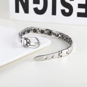 Close-up of men's silver magnetic bracelet with belt buckle clasp on ceramic tray