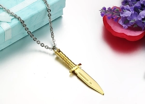 Detail of a gold dagger pendant with textured handle on a stainless steel chain