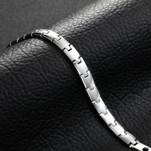 Macro shot of polished stainless steel men's magnetic bracelet on black leather background