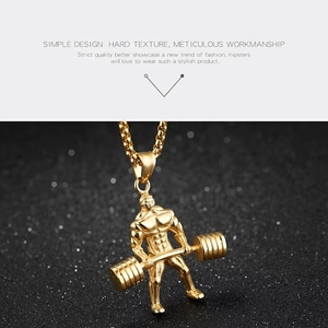 Détail d'un pendentif homme musclé plaqué or avec haltère sur un fond noir texturé